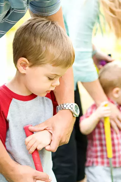 father helping son at mini golf course